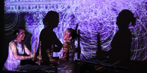 A rather complicated picture of two people playing what seem to be flutes, and their projected shades caused by the purple light of beamers creating many circles